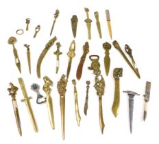 A group of Victorian and later copper and brass paper knives, with variously decorated terminals. (q