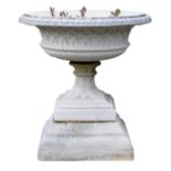 A reconstituted stone garden urn, circular top with a leaf cast border, tapering column, and a squar