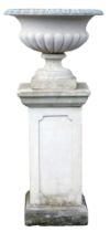 A reconstituted stone garden urn, of part fluted form, on a rectangular plinth with panelled sides,