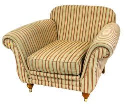 A large deep seated armchair, with gold and red striped fabric, on reeded turned legs with brass cas