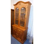 A pine bookcase with cupboard base, bookcase with two glazed panelled doors, carved sun or flower mo