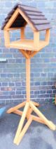 A brown wood stained bird feeding table, 156cm high.