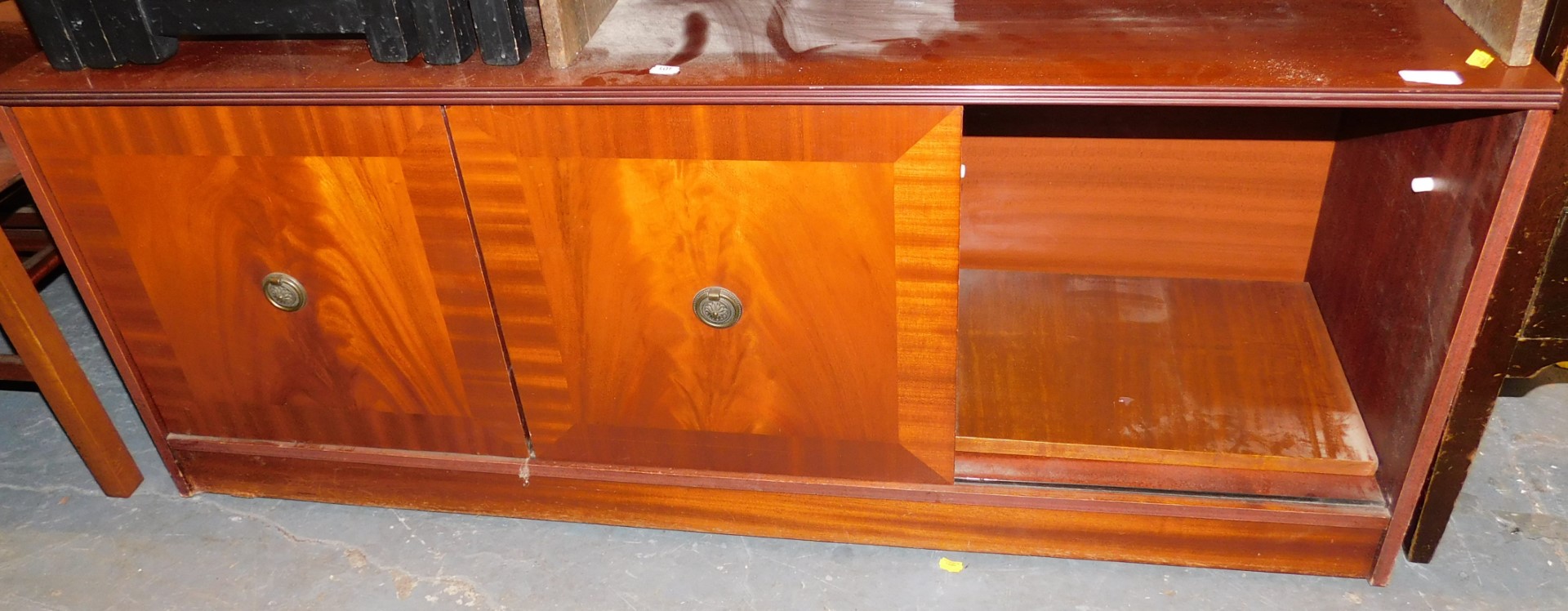 A mahogany hi-fi cabinet, with two sliding doors, on a plinth base.