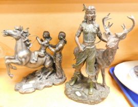 Two Native American Indian statues, one with female standing by deer, the other with male and child