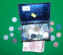A cash tin containing various British coins and a ten shilling banknote.