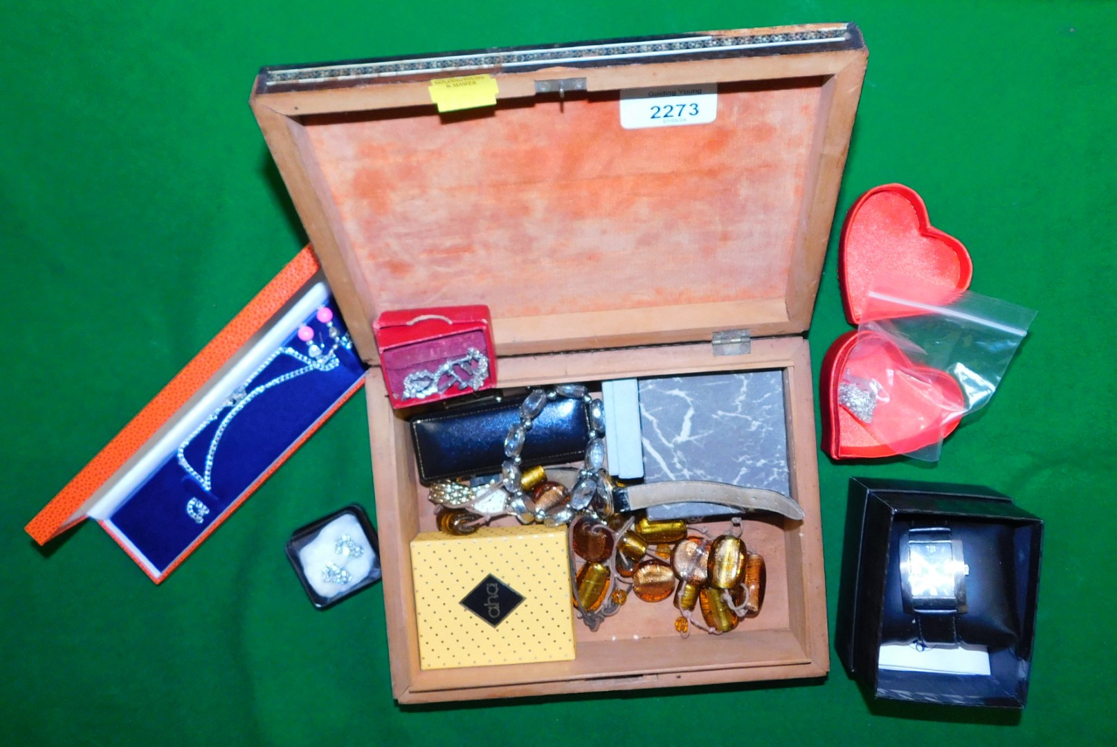 A small marquetry wooden box containing various items of costume jewellery, including a watch, neckl