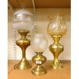 Three oil lamps, brass and glass, glass shades with brass reservoirs, all converted to electric, the