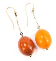 A pair of amber drop earrings, the oblong beads with pierced centre, one butterscotch, one lightly