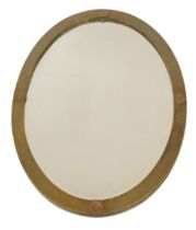 An early 20thC hammered brass oval wall mirror, with copper laurel leaf decoration at four points,