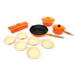 A group of Le Creuset cast iron wares in orange, to include milk pan and lid, 17cm diameter,