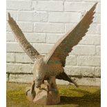 A cast metal figure modelled as an eagle, with wings outswept standing on a rocky plinth, 64cm