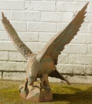 A cast metal figure modelled as an eagle, with wings outswept standing on a rocky plinth, 64cm