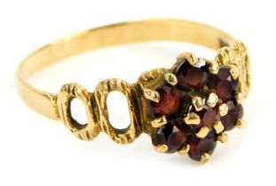 A 9ct gold dress ring, the central garnet cluster claw set, with abstract pierced shoulders, ring
