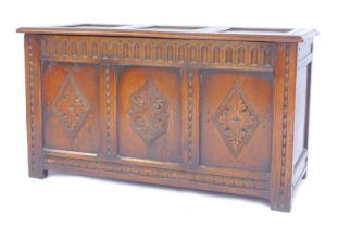 An oak coffer, the hinged three panelled top enclosing a vacant interior, the front with three
