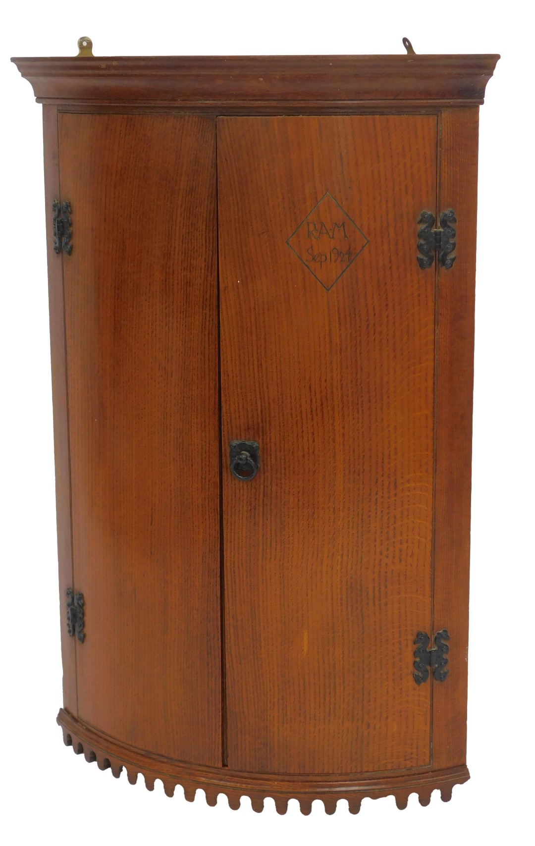 An early 20thC oak bow fronted corner cabinet, the top with a moulded edge above two doors, one