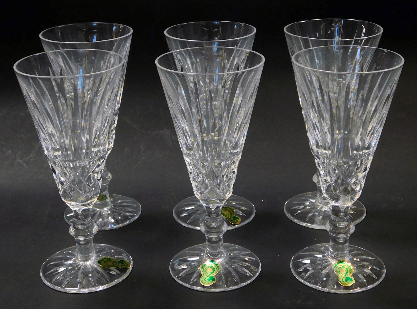 A set of six Waterford crystal Tramore pattern fluted champagne glasses, some with paper labels,