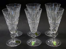 A set of six Waterford crystal Tramore pattern fluted champagne glasses, some with paper labels,