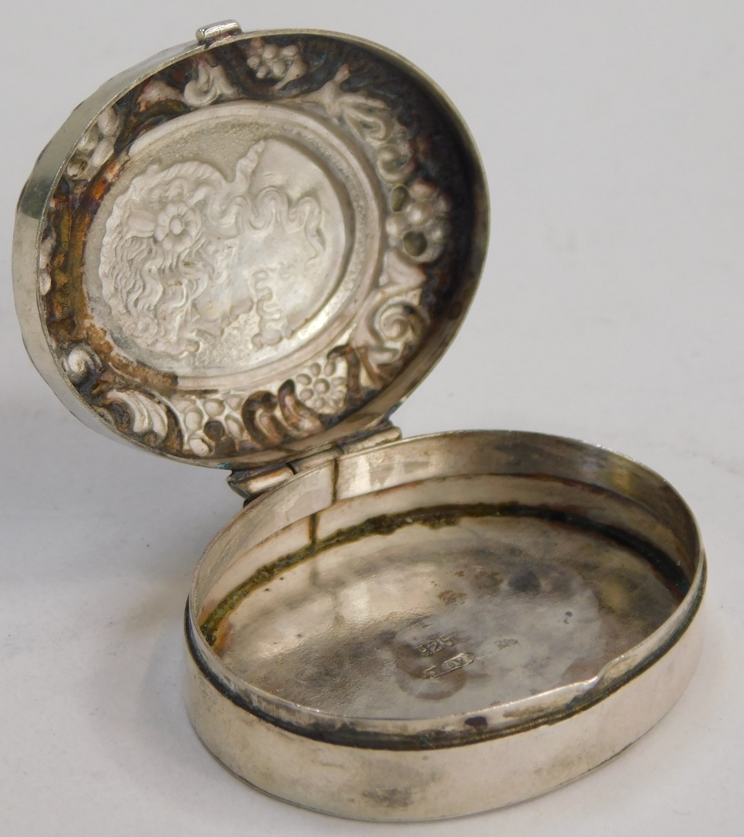 A white metal pill box, of circular design with hammered female head and flowing scroll floral - Image 2 of 3