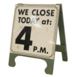 A blue painted A frame board, the white sign with black writing and border for We Close Today at