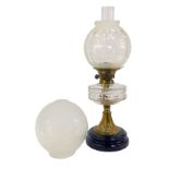 A late Victorian oil lamp, with clear glass central reservoir, on an embossed brass stem, raised