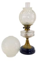 A late Victorian oil lamp, with clear glass central reservoir, on an embossed brass stem, raised
