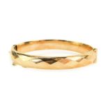 A 9ct gold hinged bangle, the half hinged design with hammered triangular cut design, with bolt