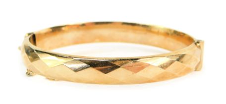 A 9ct gold hinged bangle, the half hinged design with hammered triangular cut design, with bolt