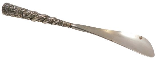 An Indian white metal handled shoe horn, formed as dragons and flowers, with rubbed hallmarks