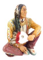 A 20thC resin figure modelled as a Native American seated, with feathered fan, 43cm high.