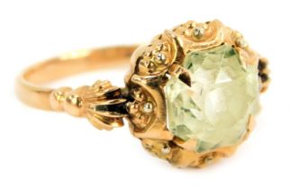 An Edwardian dress ring, set with octagonal cut and faceted pale green paste stone, in four claw