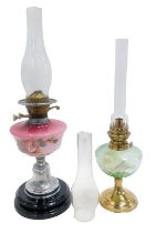 An early 20thC oil lamp, the opaque glass central reservoir decorated with flowers against a