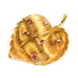 A moulded leaf brooch, set with three round brilliant cut and raised rubies, each in four claw