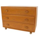 An Ercol elm chest, of three drawers, on castors, model number 412, bearing label, 66cm high, 92cm