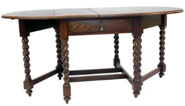 An early 20thC oak gate leg table, the top with a rounded edge, raised on spiral turned legs