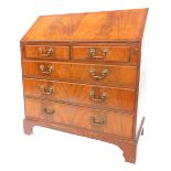 A 20thC mahogany and flamed mahogany bureau in George III style, the fall enclosing an arrangement