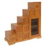 An Eastern mango wood cabinet, of stepped design, with an arrangement of nine drawers, with an