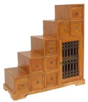 An Eastern mango wood cabinet, of stepped design, with an arrangement of nine drawers, with an