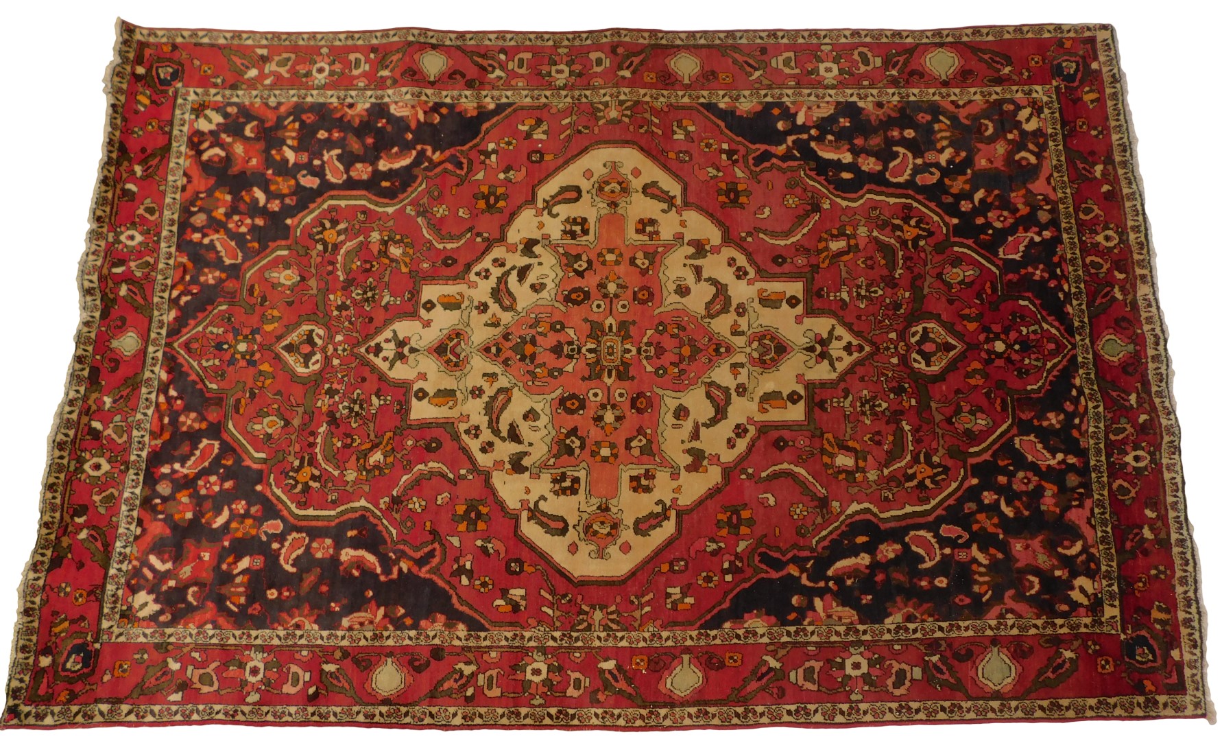 A Persian red ground rug, decorated centrally with flowers within one wide and two narrow borders,
