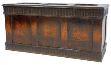 An oak coffer, the three-panelled hinged top enclosing a vacant interior, the front with three