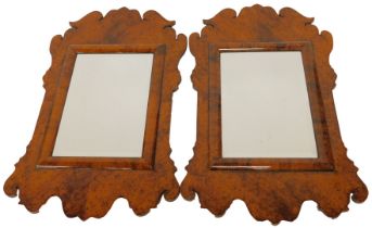 A pair of 20thC simulated burr wood fret style wall mirrors, each with a rectangular bevelled mirror