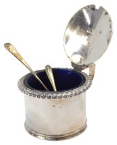 A silver mustard pot, with a fluted border and shell capped thumb piece, with blue glass liner,