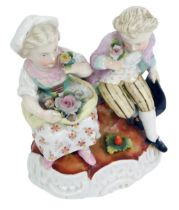 A late 19thC Sitzendorf porcelain figure group, modelled as two seated children with flowers, on