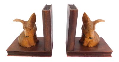 A pair of early 20thC oak L shaped bookends, each surmounted by a carved figure of a dog, 16cm