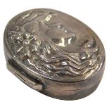 A silver pill box, the oval pill box with hammered decoration of a female with flowing hair and