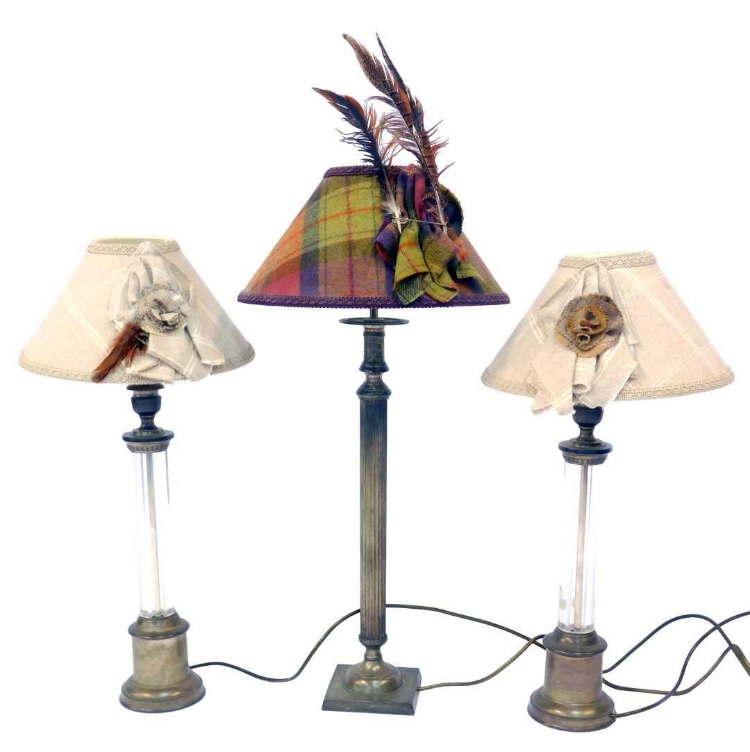 A pair of 20thC table lamps, each with a central glass column and cast metal mounts, with a tweed