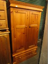 A pine two door wardrobe, with a single drawer on a plinth.