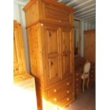 A pine double wardrobe, with over tier storage cupboard, two panelled doors above three drawers,