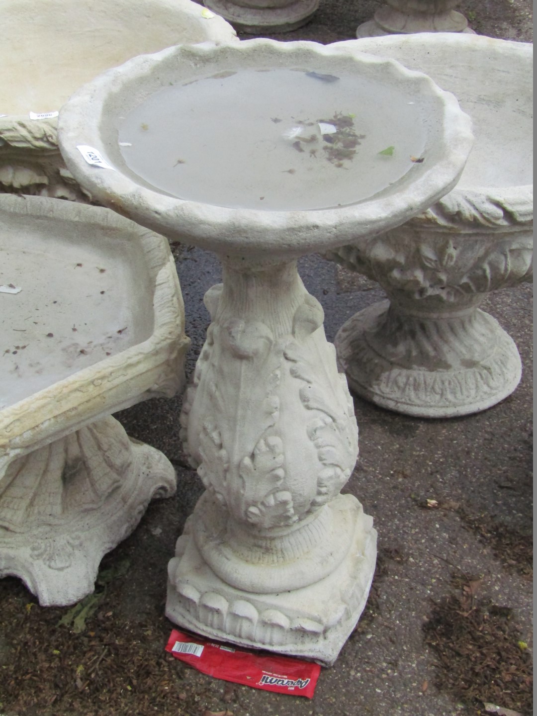 A reconstituted stone birdbath, the circular top on a leaf moulded square set column, 60cm high,