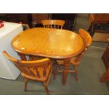 A pine oval kitchen table and three stick back chairs.