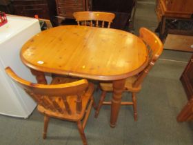 A pine oval kitchen table and three stick back chairs.